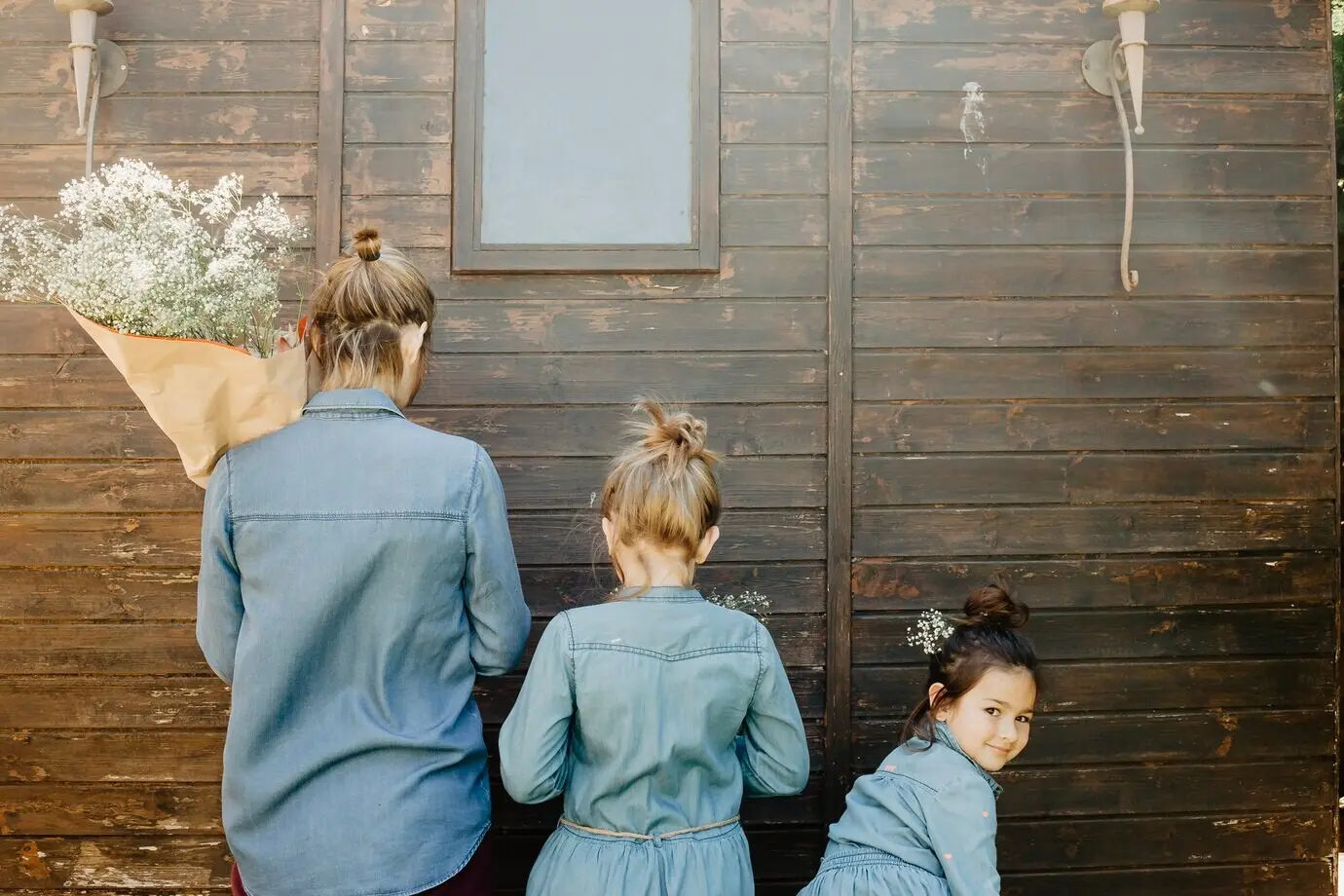 Mutter und Töchter mit Blumen in der Nähe eines Schuppens